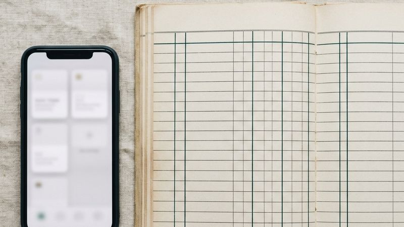 A phone with document cards beside a ledger split into two column groups.