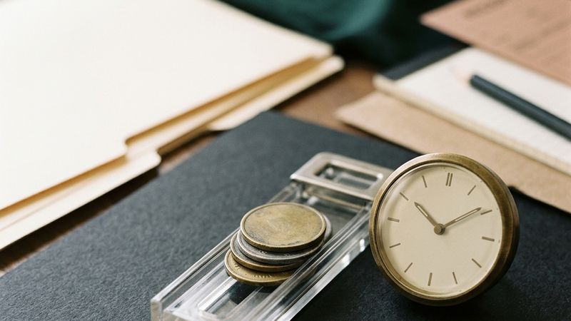 A stack of tokens behind a half-open latch beside a clock.