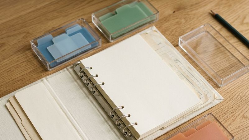 Five trays of index tabs around an open binder, one tray empty.